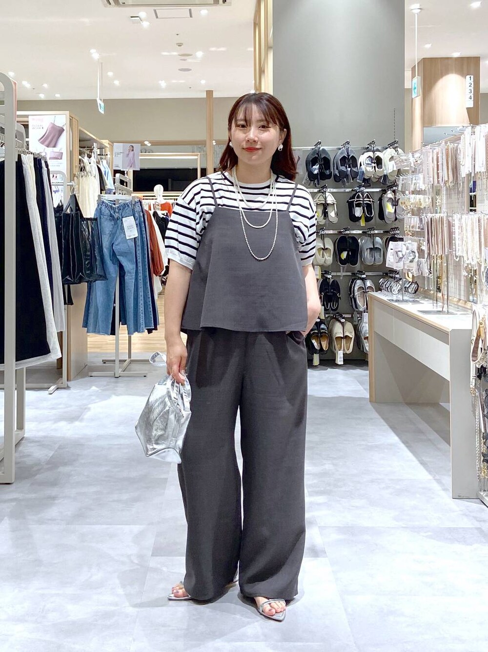 シルバー系のショルダーバッグ、ホワイト系のTシャツ/カットソー、シルバー系のサンダルを着用したレディースの夏コーディネートの1枚目の写真