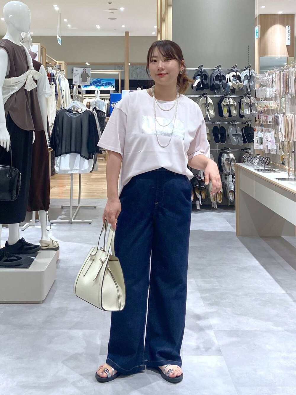 ホワイト系のショルダーバッグ、ピンク系のTシャツ/カットソー、ブルー系のデニムパンツを着用したレディースの夏コーディネートの1枚目の写真