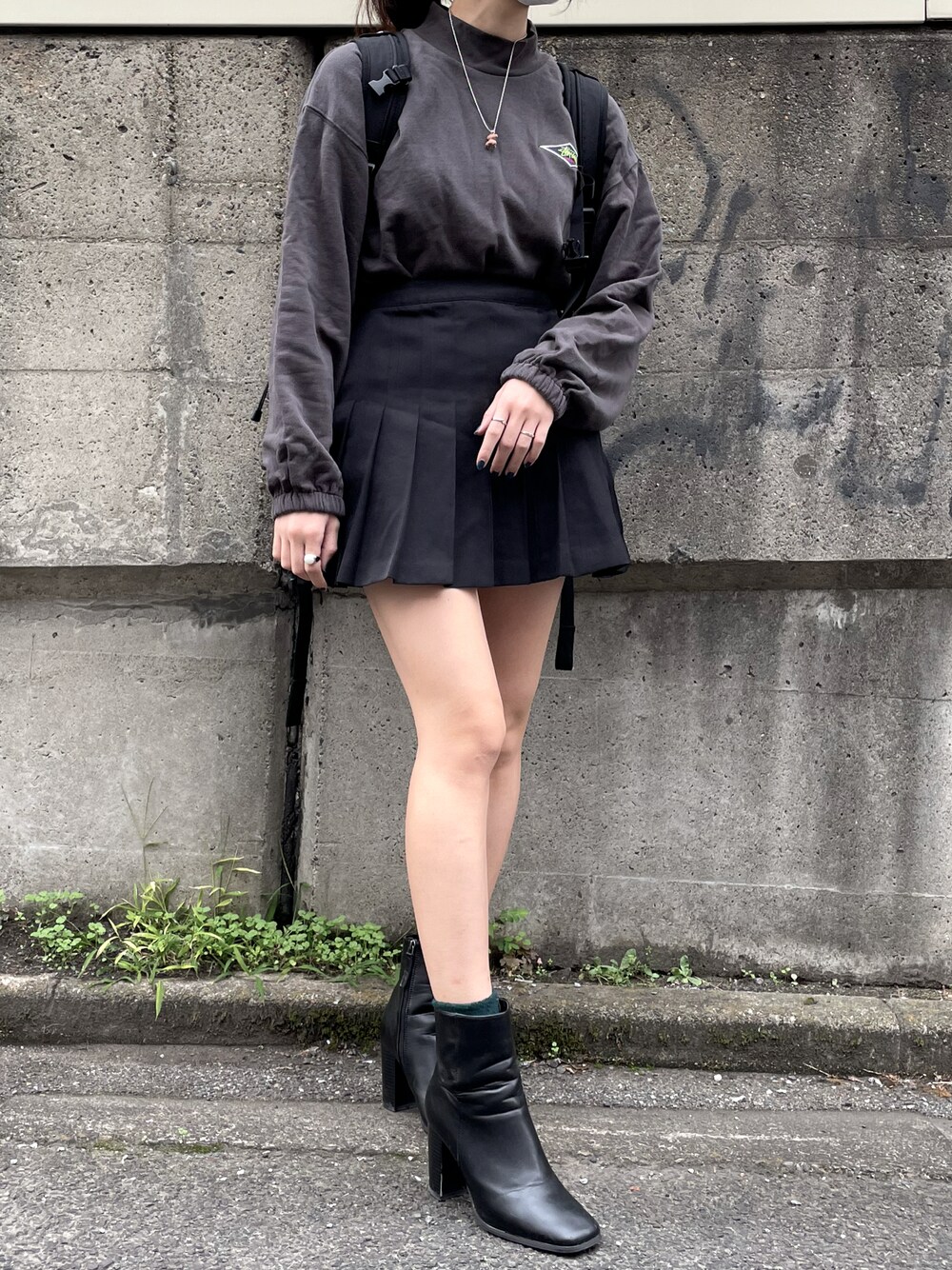 グレー系のスウェット、ブラック系のスカート、ブラック系のブーツを着用したレディースの秋コーディネートの1枚目の写真