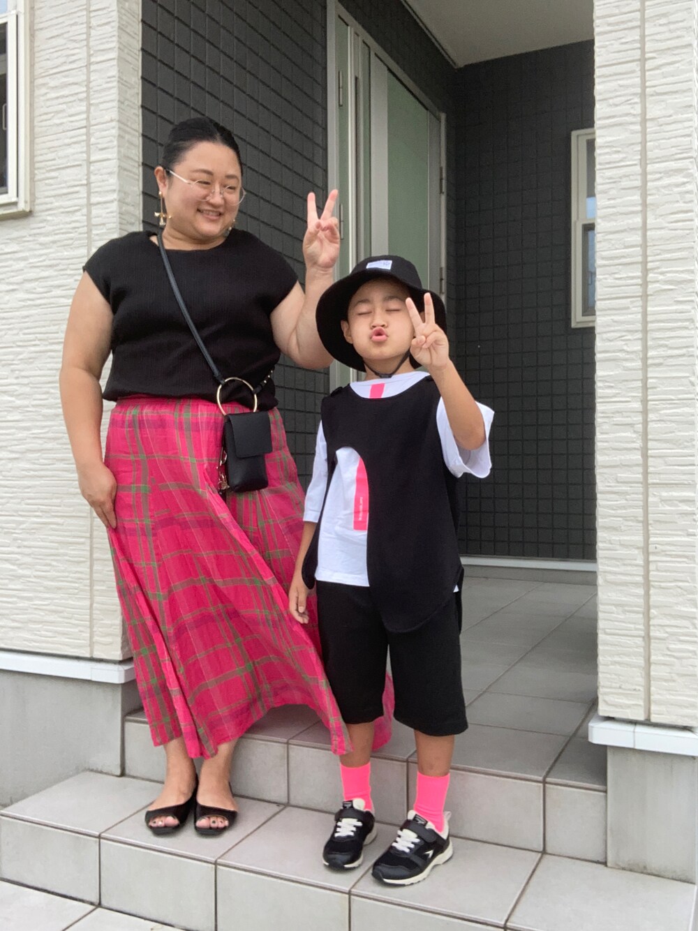 ブラック系のTシャツ/カットソー、ピンク系のスカート、ブラック系のサンダルを着用したレディースの秋コーディネートの1枚目の写真