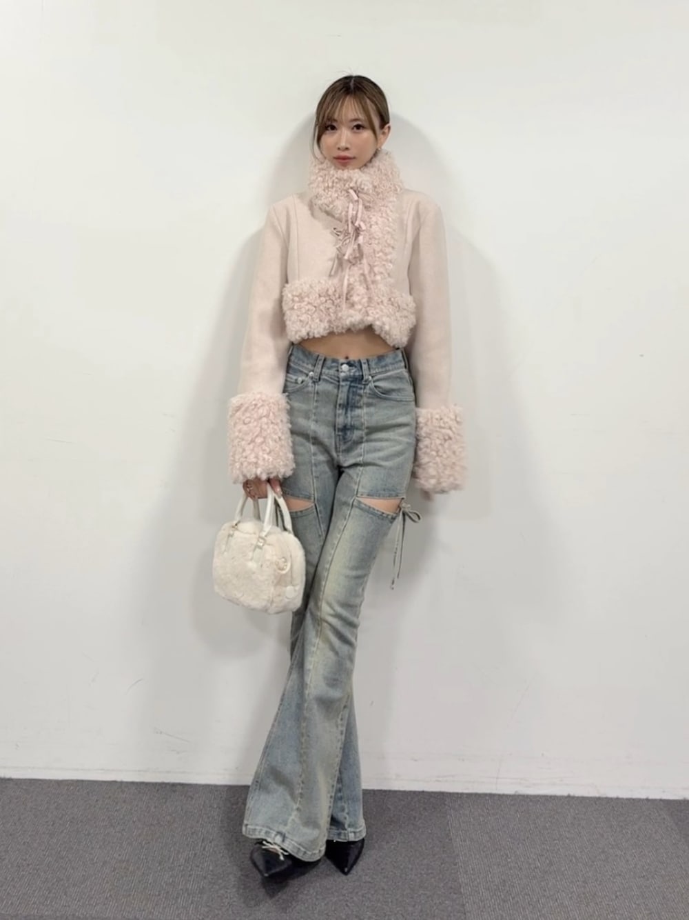 ブルー系のデニムパンツ、ブラック系のパンプス、ホワイト系のハンドバッグを着用したレディースの夏コーディネートの1枚目の写真
