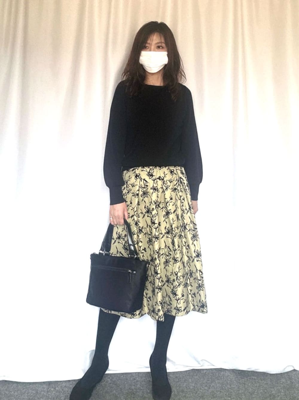 ブラック系のニット/セーター、グリーン系のスカートを着用したレディースの秋コーディネートの1枚目の写真