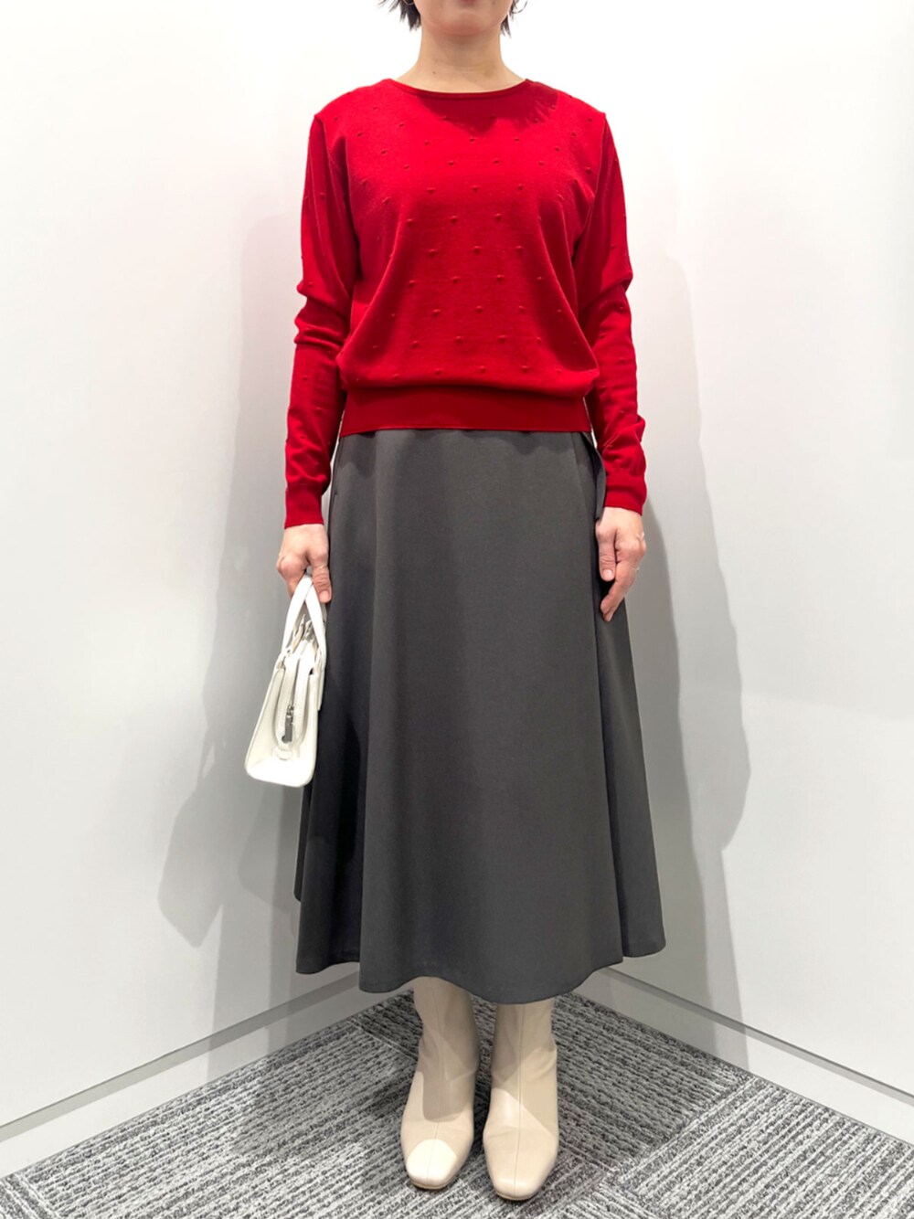 グレー系のスカート、レッド系のニット/セーターを着用したレディースの秋コーディネートの1枚目の写真