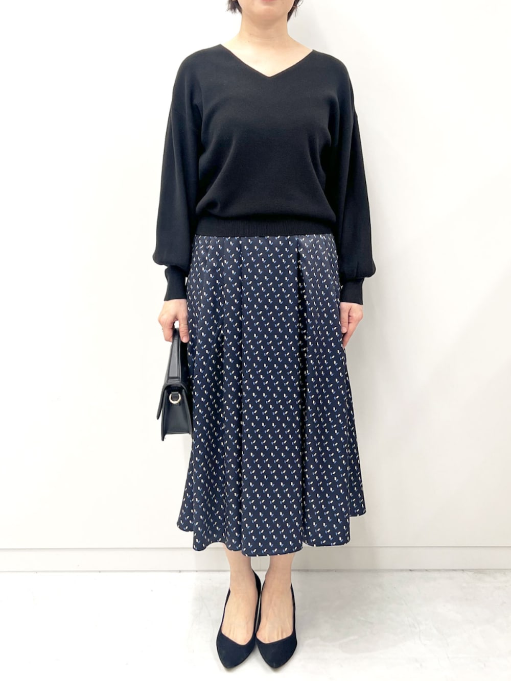 ブラック系のニット/セーター、ブルー系のスカートを着用したレディースの秋コーディネートの1枚目の写真