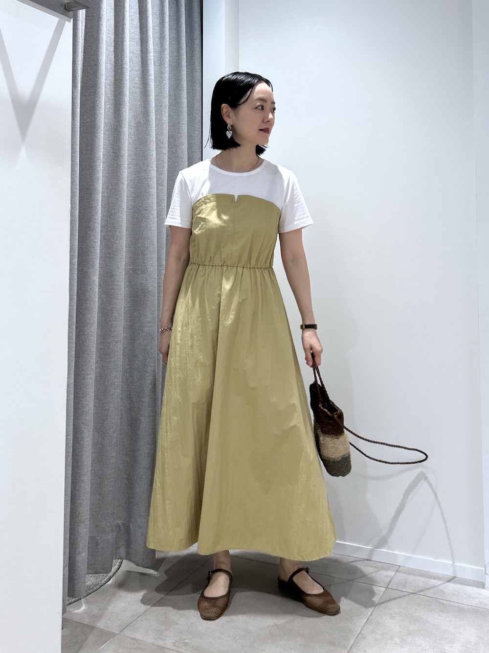 ベージュ系のワンピース、ゴールド系のハンドバッグ、ブラウン系のサンダルを着用したレディースの夏コーディネートの1枚目の写真