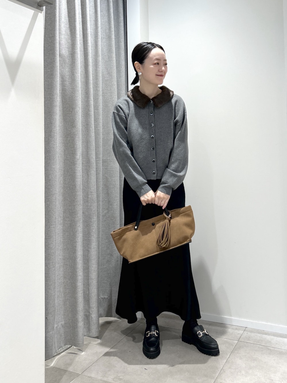 グレー系のカーディガン/ボレロ、ブラック系のスカート、ベージュ系のトートバッグを着用したレディースの秋コーディネートの1枚目の写真