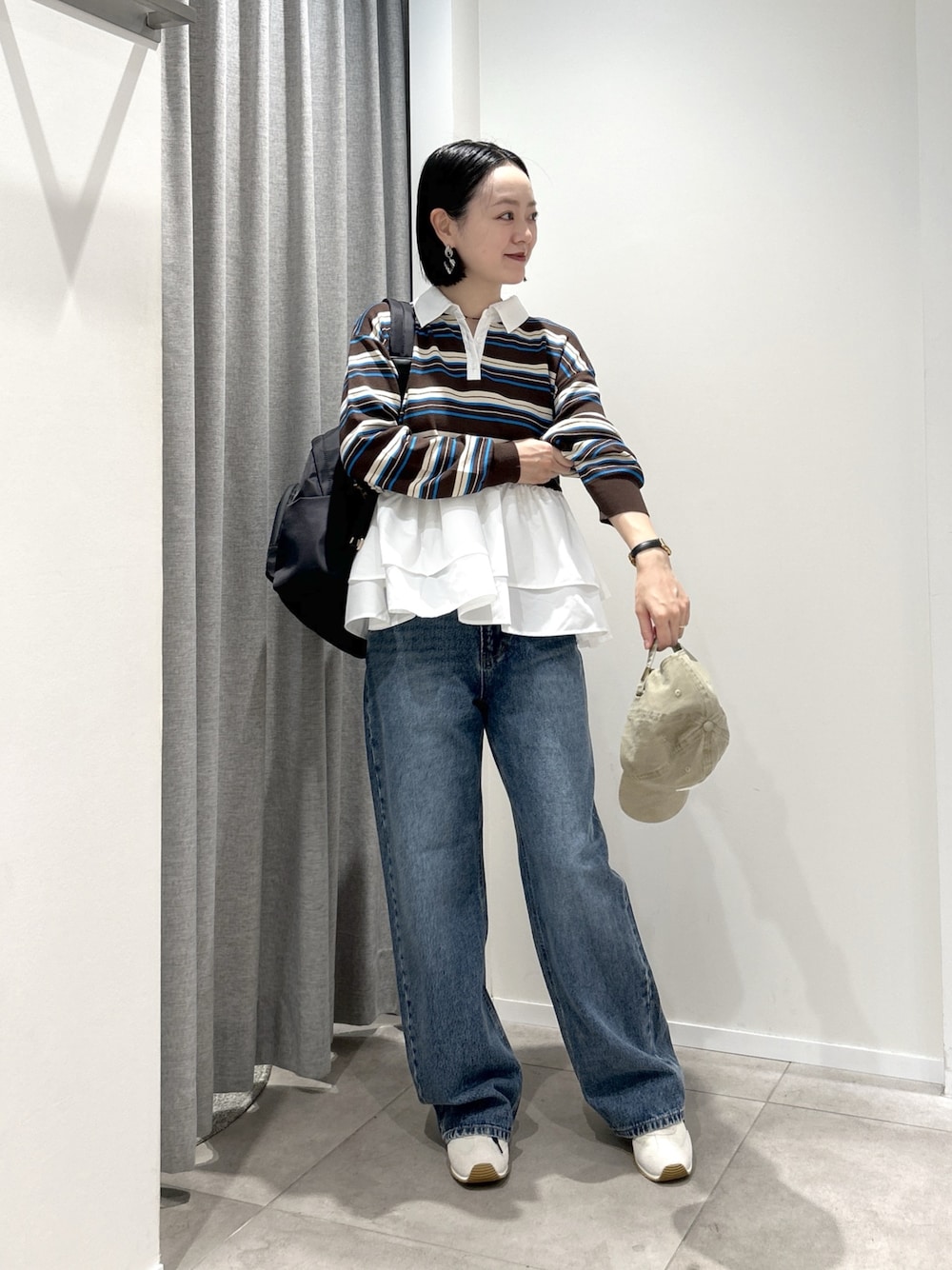 ブルー系のデニムパンツ、ブラック系のバックパック/リュック、ブラウン系のニット/セーターを着用したレディースの秋コーディネートの1枚目の写真