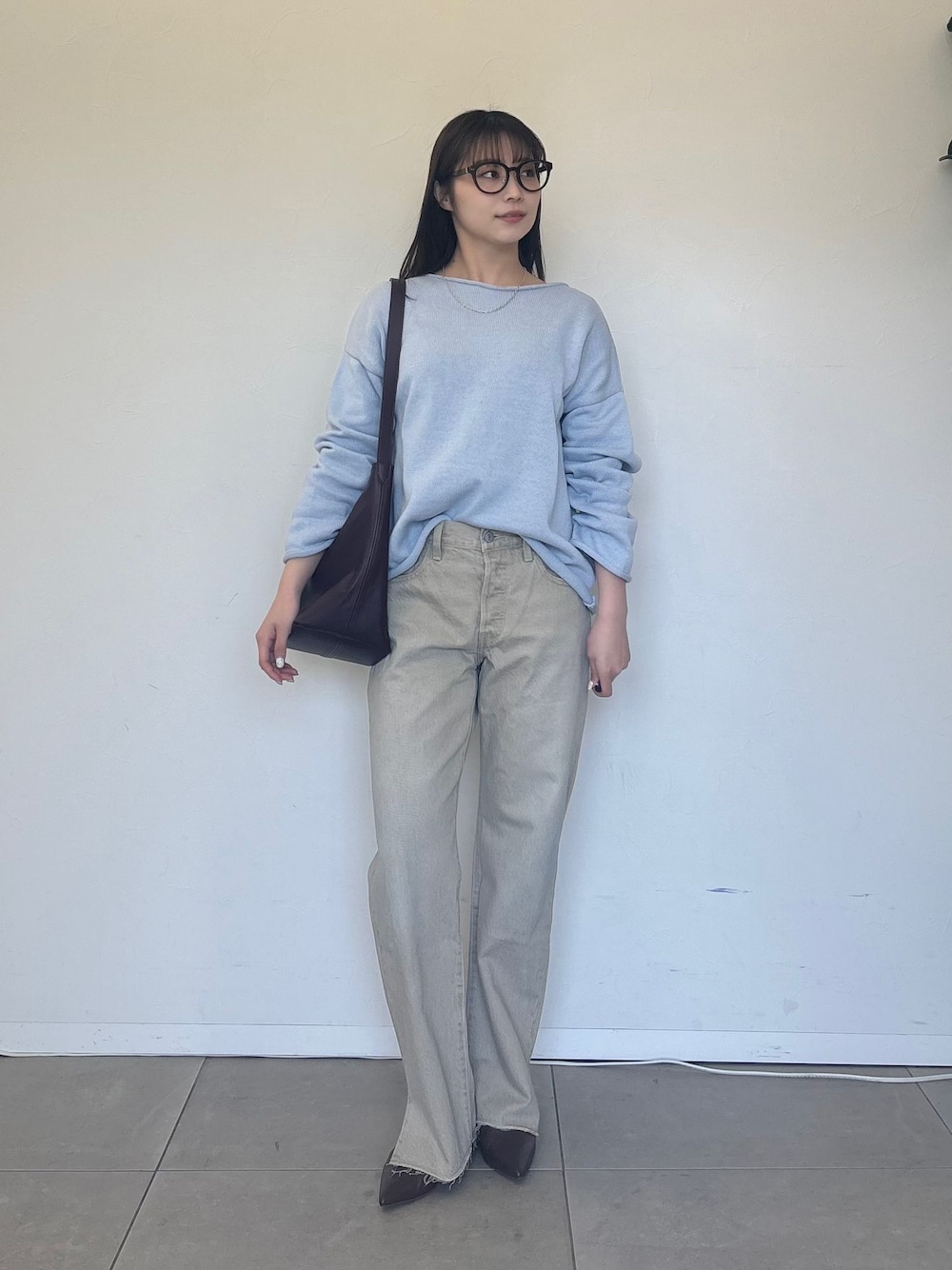 ベージュ系のデニムパンツ、ブルー系のニット/セーター、レッド系のショルダーバッグを着用したレディースの冬コーディネートの1枚目の写真