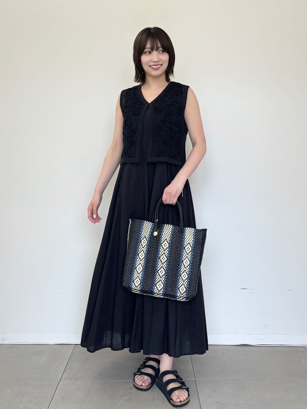 ブラック系のワンピース、ブラック系のシャツ/ブラウス、ブルー系のトートバッグを着用したレディースの夏コーディネートの1枚目の写真
