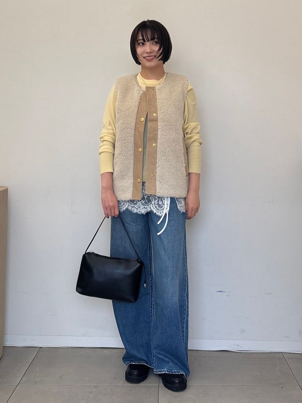 ホワイト系のその他アウター、ブルー系のデニムパンツ、イエロー系のニット/セーターを着用したレディースの秋コーディネートの1枚目の写真