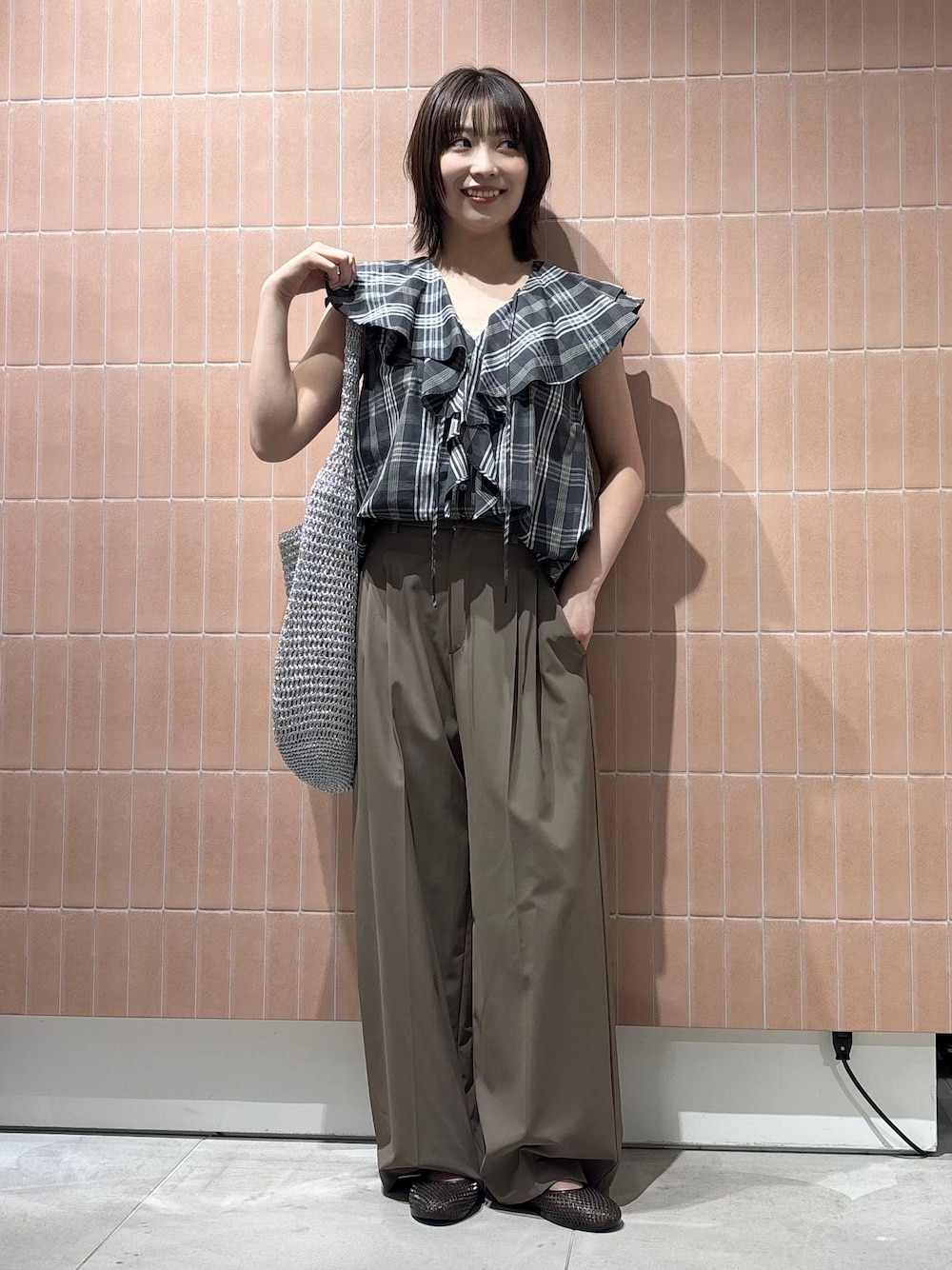 ベージュ系のスラックス、シルバー系のショルダーバッグ、ブラック系のパンプスを着用したレディースの夏コーディネートの1枚目の写真