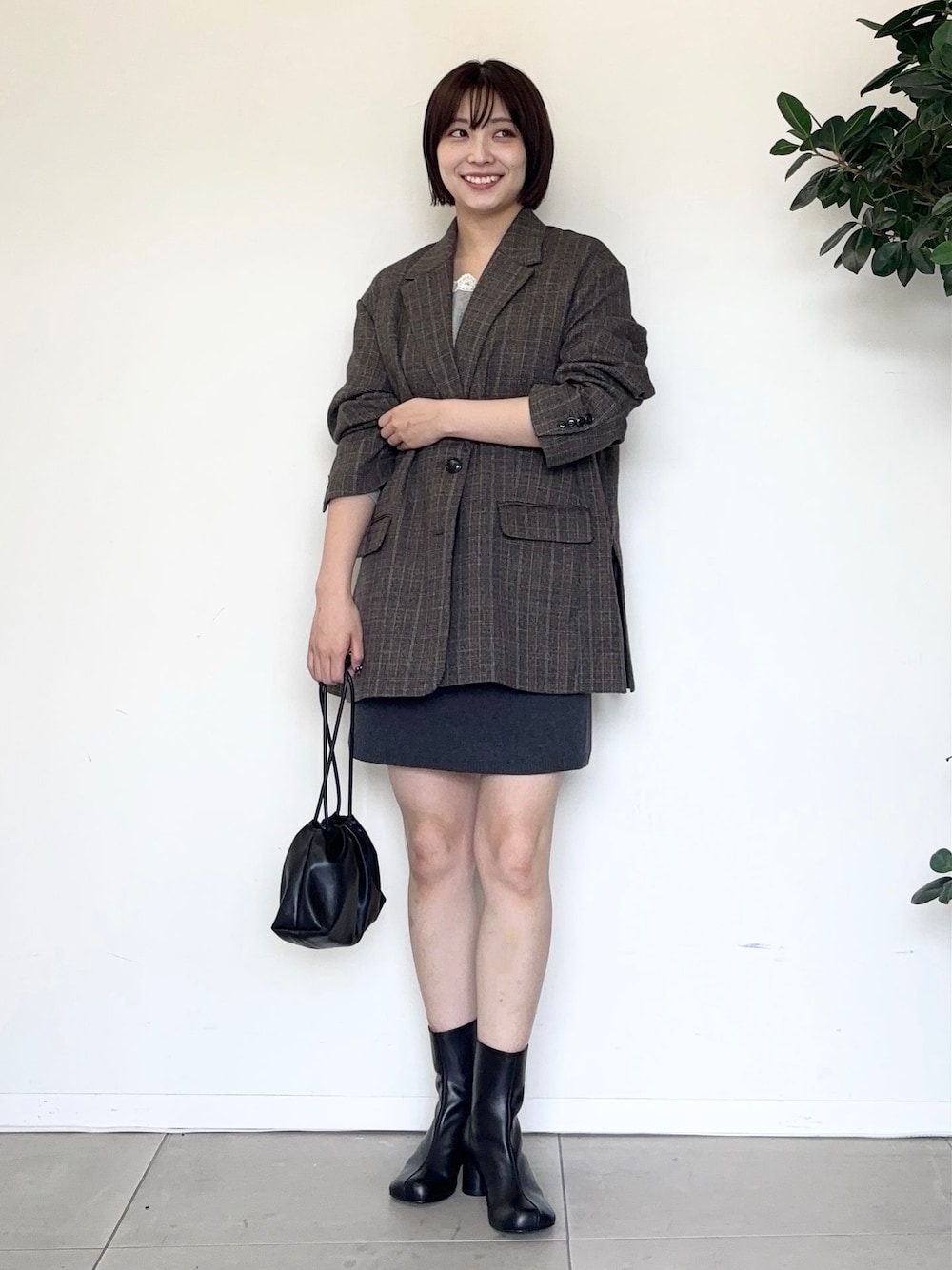 グレー系のスカート、グレー系のTシャツ/カットソー、ブラック系のクラッチバッグを着用したレディースの秋コーディネートの1枚目の写真