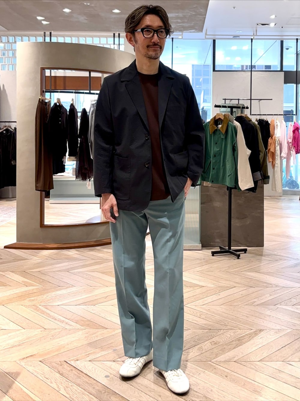 ブラック系のテーラードジャケット、グリーン系のスラックス、ブラウン系のTシャツ/カットソーを着用したメンズの春コーディネートの1枚目の写真