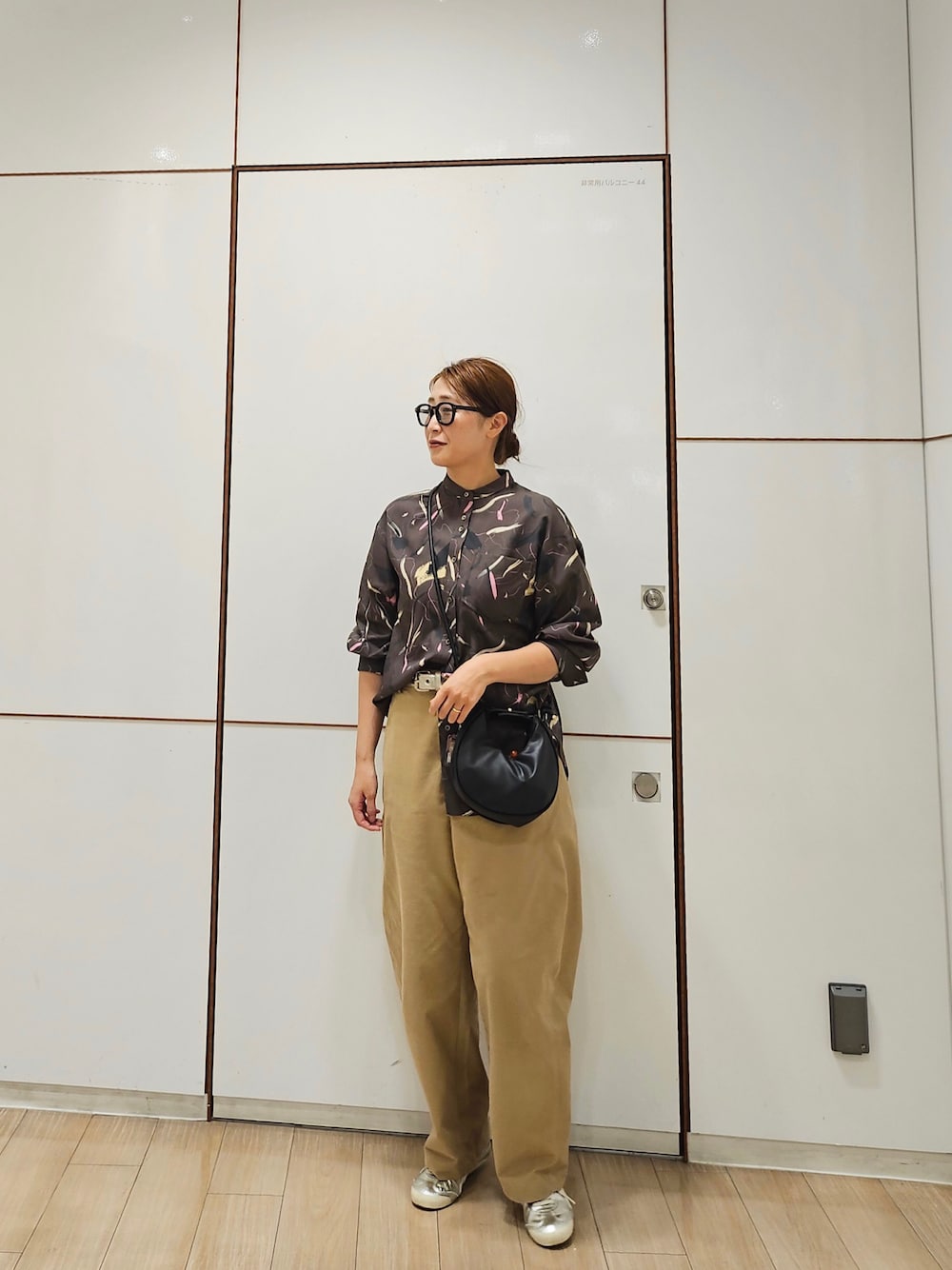 ブラウン系のシャツ/ブラウス、ベージュ系のパンツ、シルバー系のスニーカーを着用したレディースの秋コーディネートの1枚目の写真