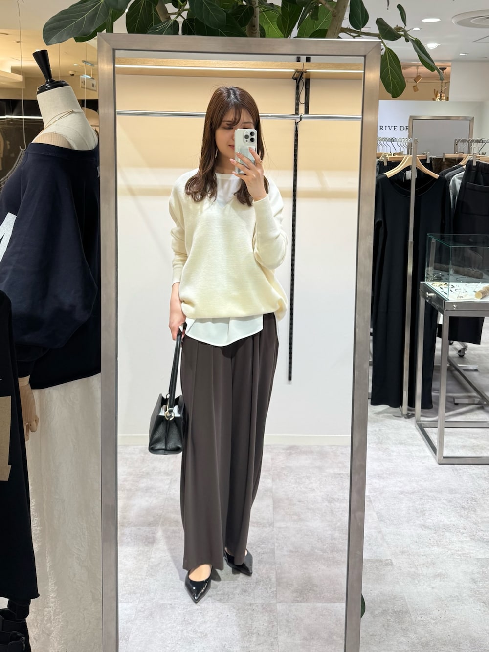 ホワイト系のニット/セーター、ブラウン系のスラックス、ホワイト系のシャツ/ブラウスを着用したレディースの冬コーディネートの1枚目の写真