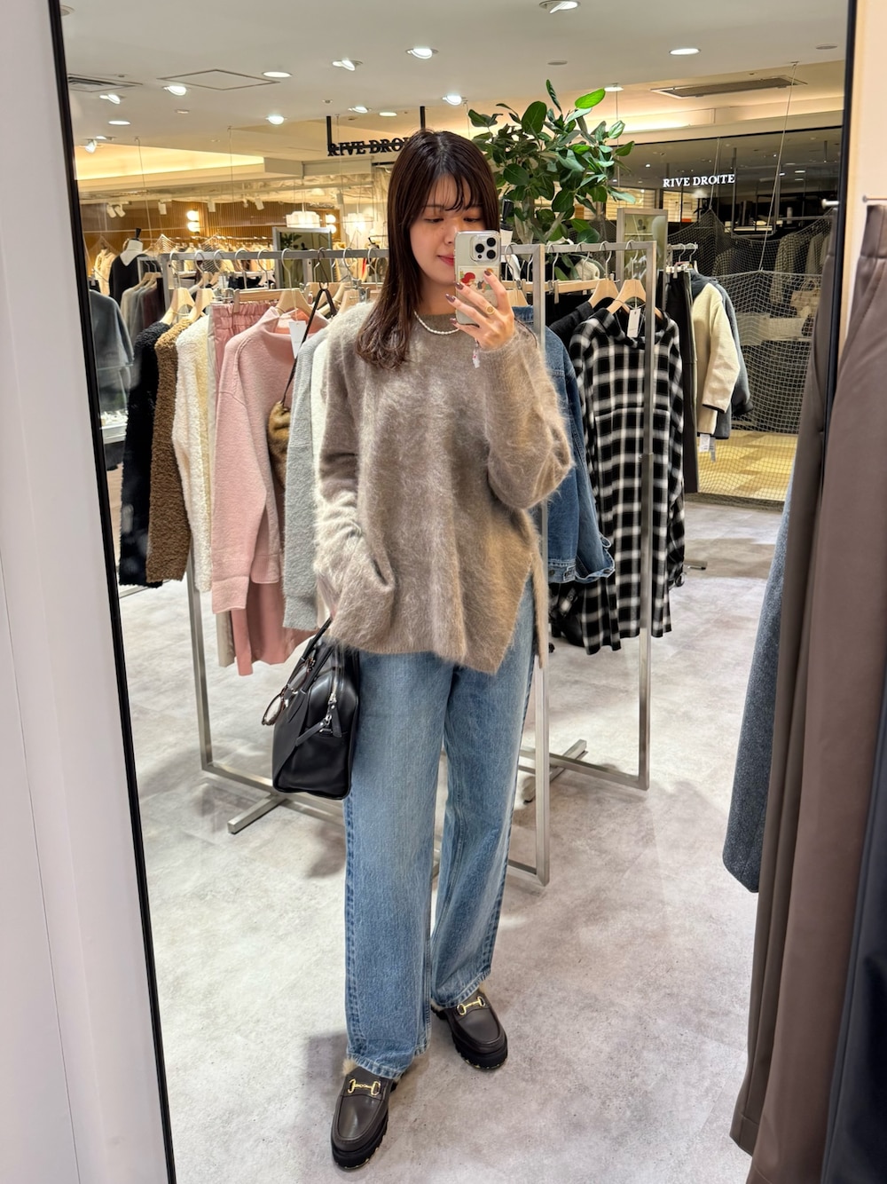 ブラウン系のニット/セーター、ブルー系のデニムパンツ、ブラック系のボストンバッグを着用したレディースの秋コーディネートの1枚目の写真