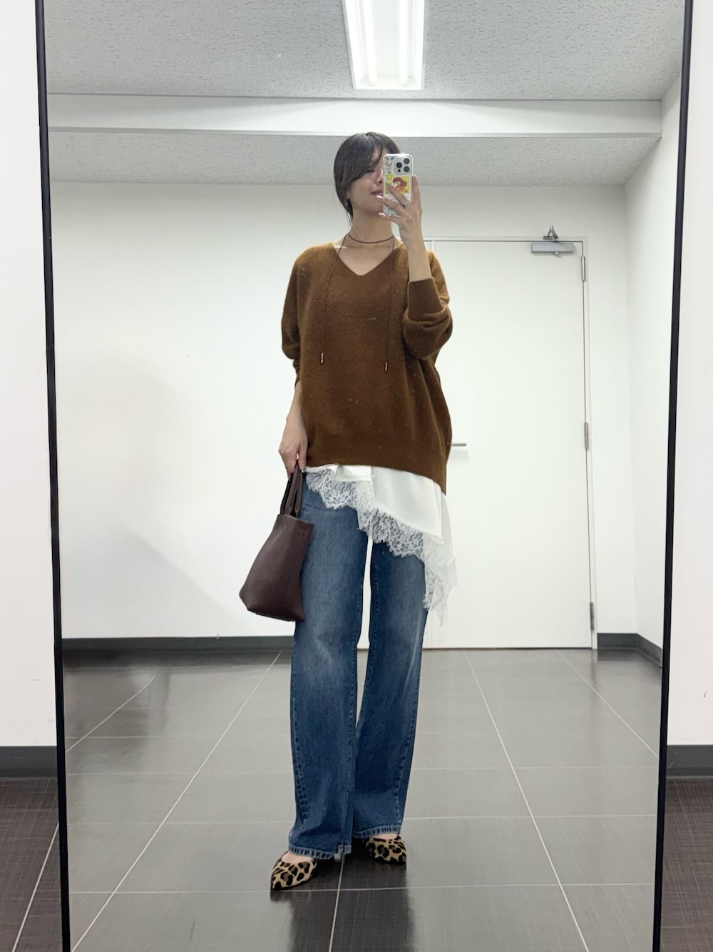 イエロー系のニット/セーター、ホワイト系のキャミソール、ブルー系のデニムパンツを着用したレディースの秋コーディネートの1枚目の写真