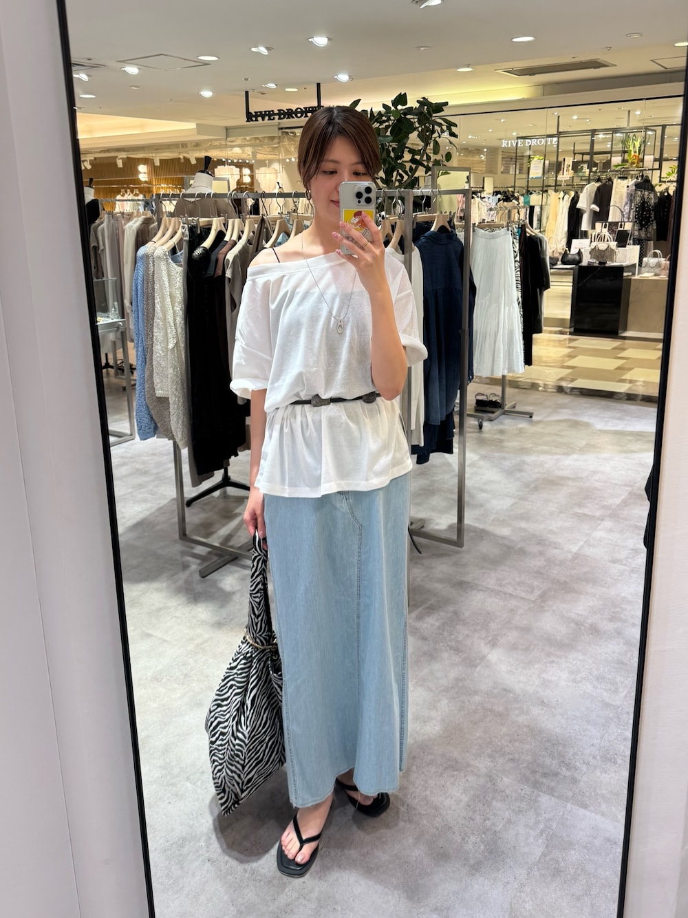 ホワイト系のTシャツ/カットソー、ブルー系のデニムスカート、ブラック系のサンダルを着用したレディースの夏コーディネートの1枚目の写真