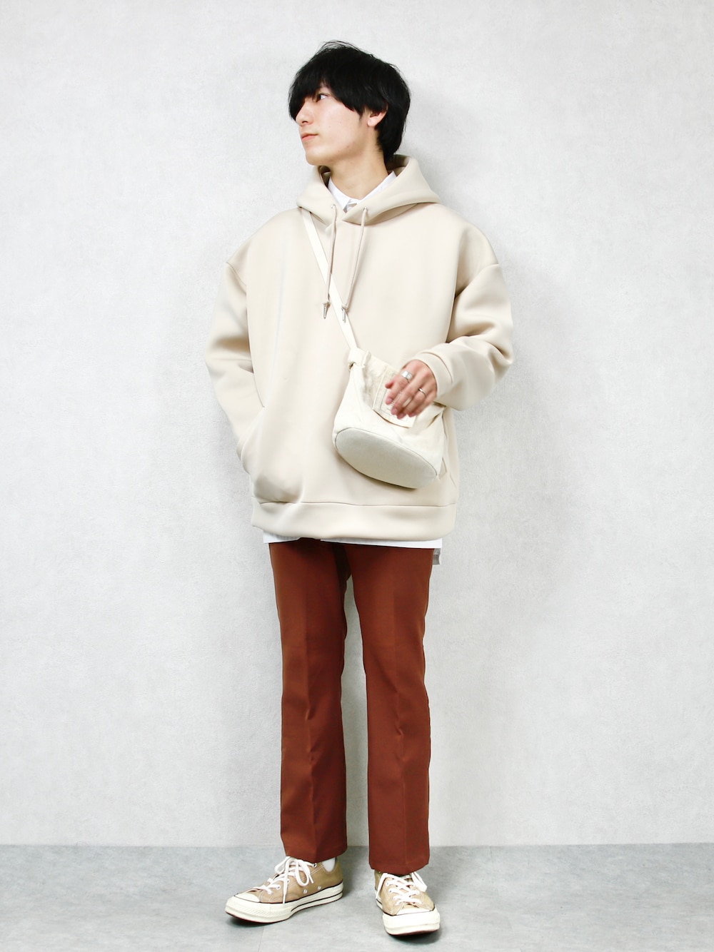 ホワイト系のスウェット、ベージュ系のショルダーバッグ、ブラウン系のスラックスを着用したメンズの冬コーディネートの1枚目の写真