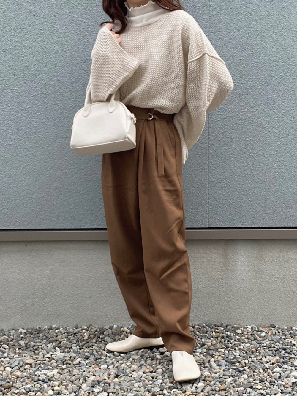 ベージュ系のニット/セーター、ホワイト系のハンドバッグ、ブラウン系のパンツを着用したレディースの冬コーディネートの1枚目の写真