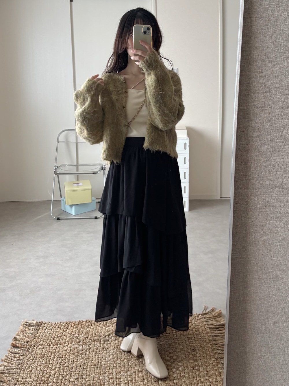 グリーン系のニット/セーター、ホワイト系のキャミソール、ブラック系のセットアップを着用したレディースの秋コーディネートの1枚目の写真