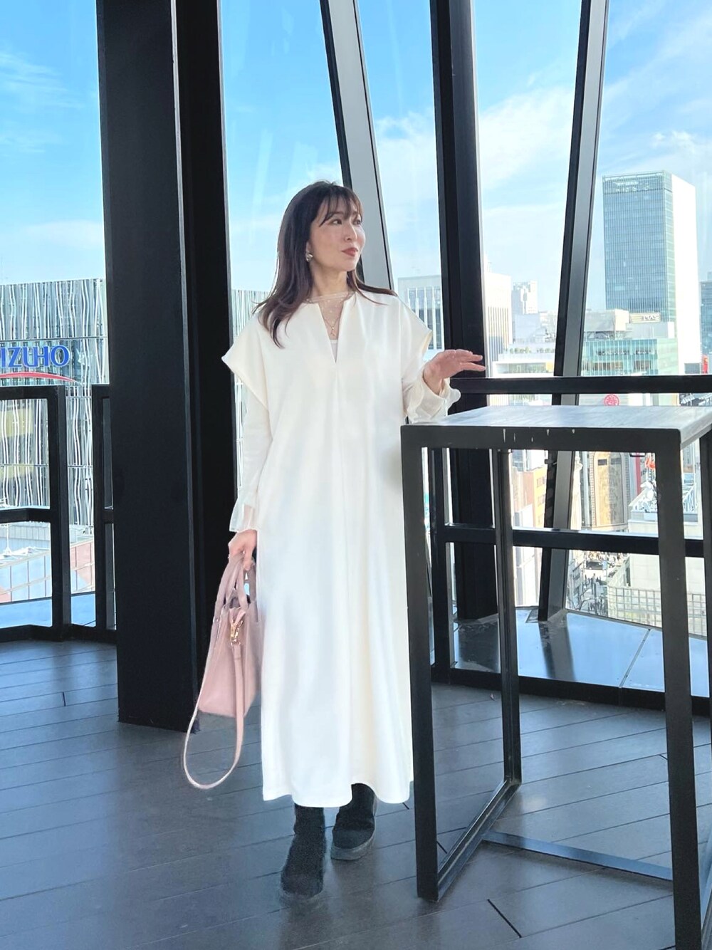 ホワイト系のワンピース、ピンク系のハンドバッグを着用したレディースの春コーディネートの1枚目の写真