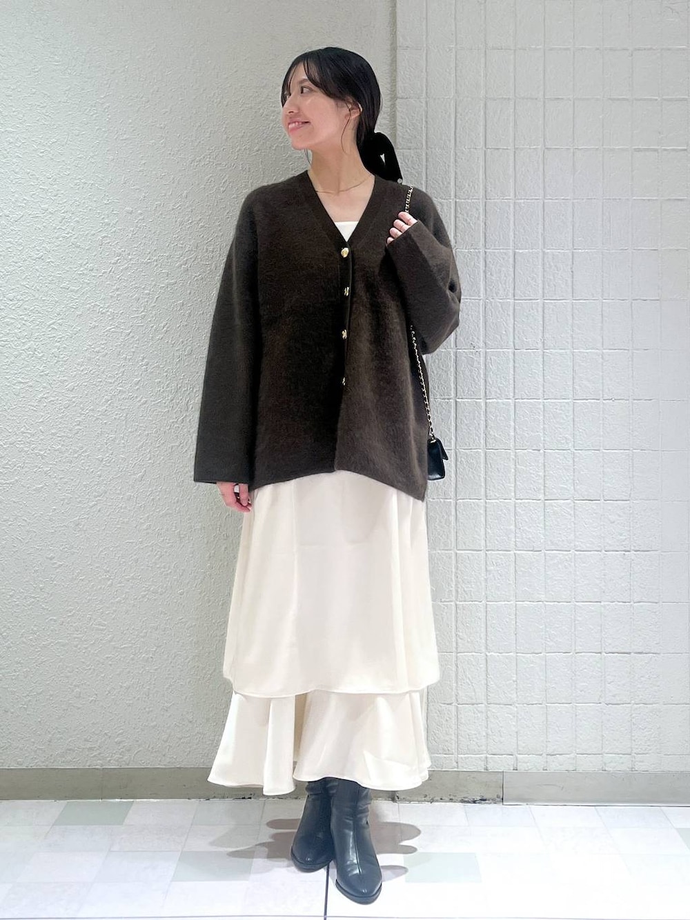 ブラウン系のカーディガン/ボレロ、ブラック系のブーツ、ホワイト系のワンピースを着用したレディースの秋コーディネートの1枚目の写真