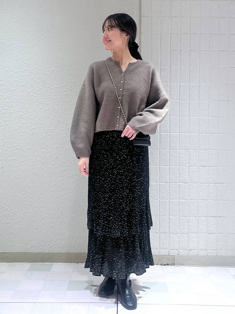 グレー系のスカート、ブラック系のブーツ、ゴールド系のネックレスを着用したレディースの秋コーディネートの1枚目の写真