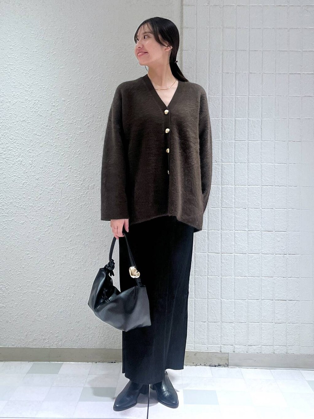 ブラウン系のカーディガン/ボレロ、ブラック系のブーツ、ブラック系のスカートを着用したレディースの秋コーディネートの1枚目の写真