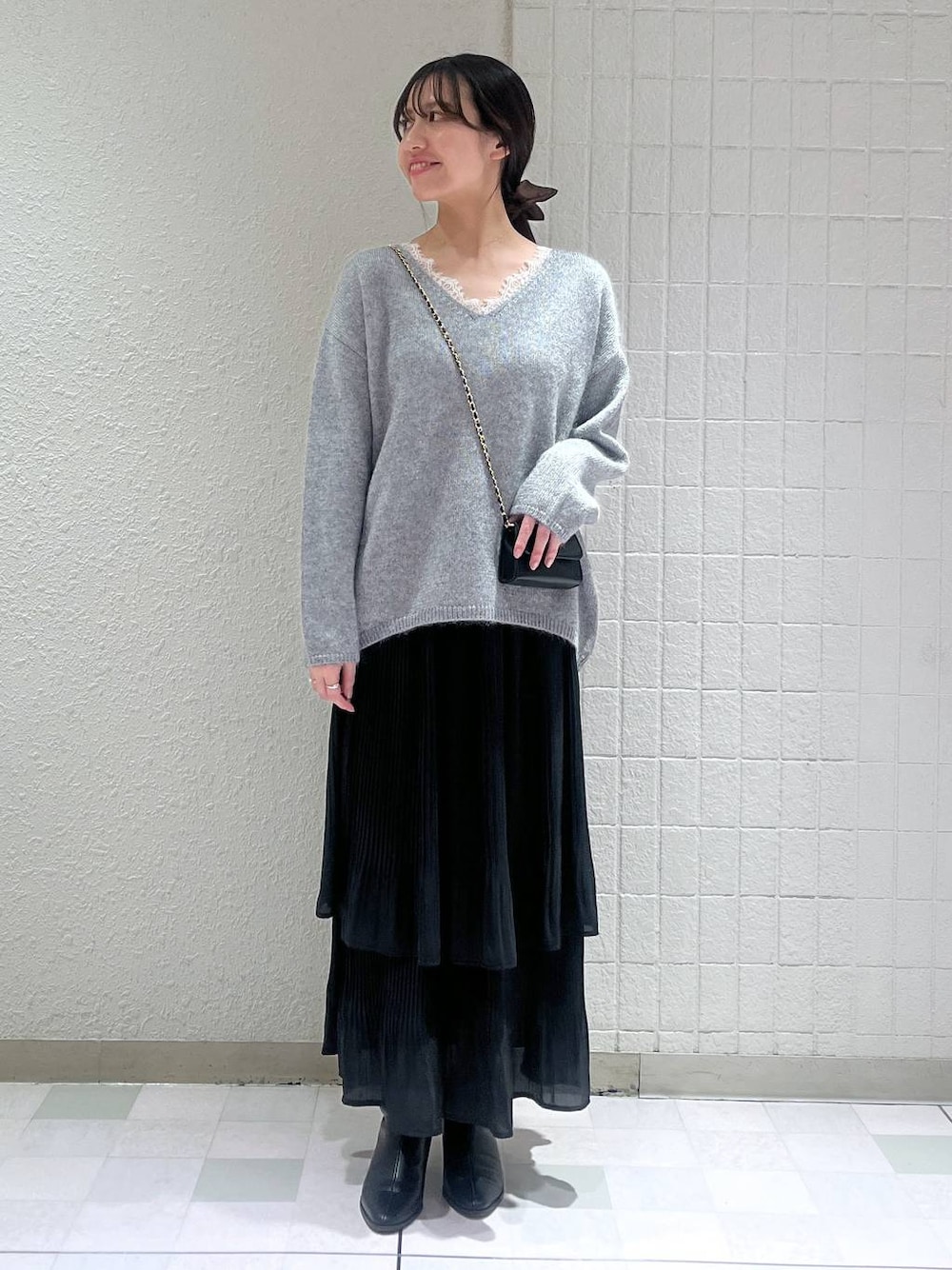 ブラック系のブーツ、ブラック系のスカート、グレー系のニット/セーターを着用したレディースの秋コーディネートの1枚目の写真