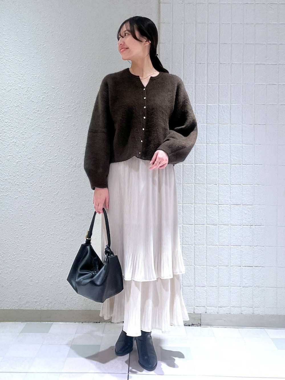 ブラック系のブーツ、ホワイト系のスカート、ブラウン系のカーディガン/ボレロを着用したレディースの秋コーディネートの1枚目の写真