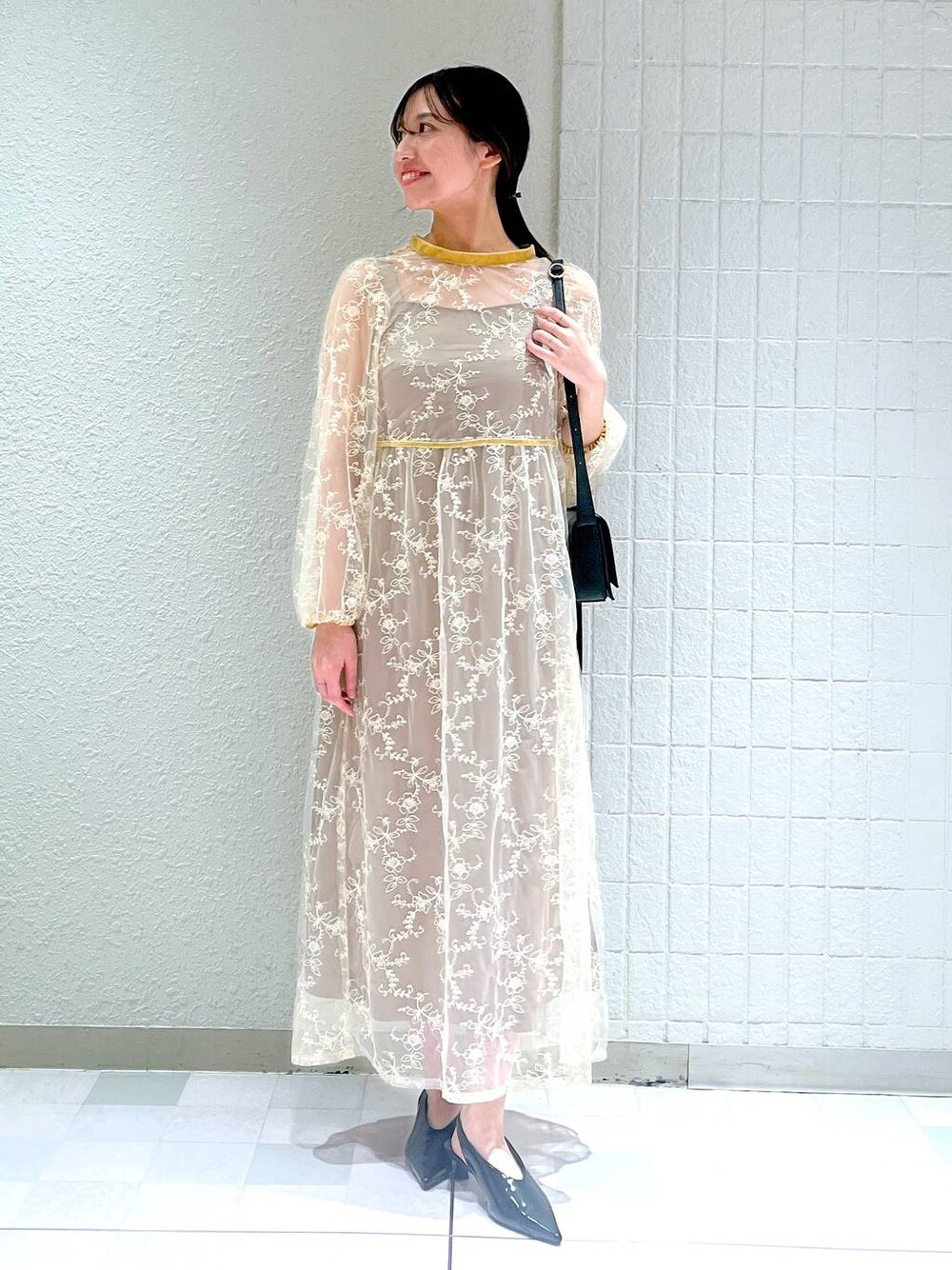 ブラック系のショルダーバッグ、ブラック系のパンプス、ベージュ系のドレスを着用したレディースの秋コーディネートの1枚目の写真