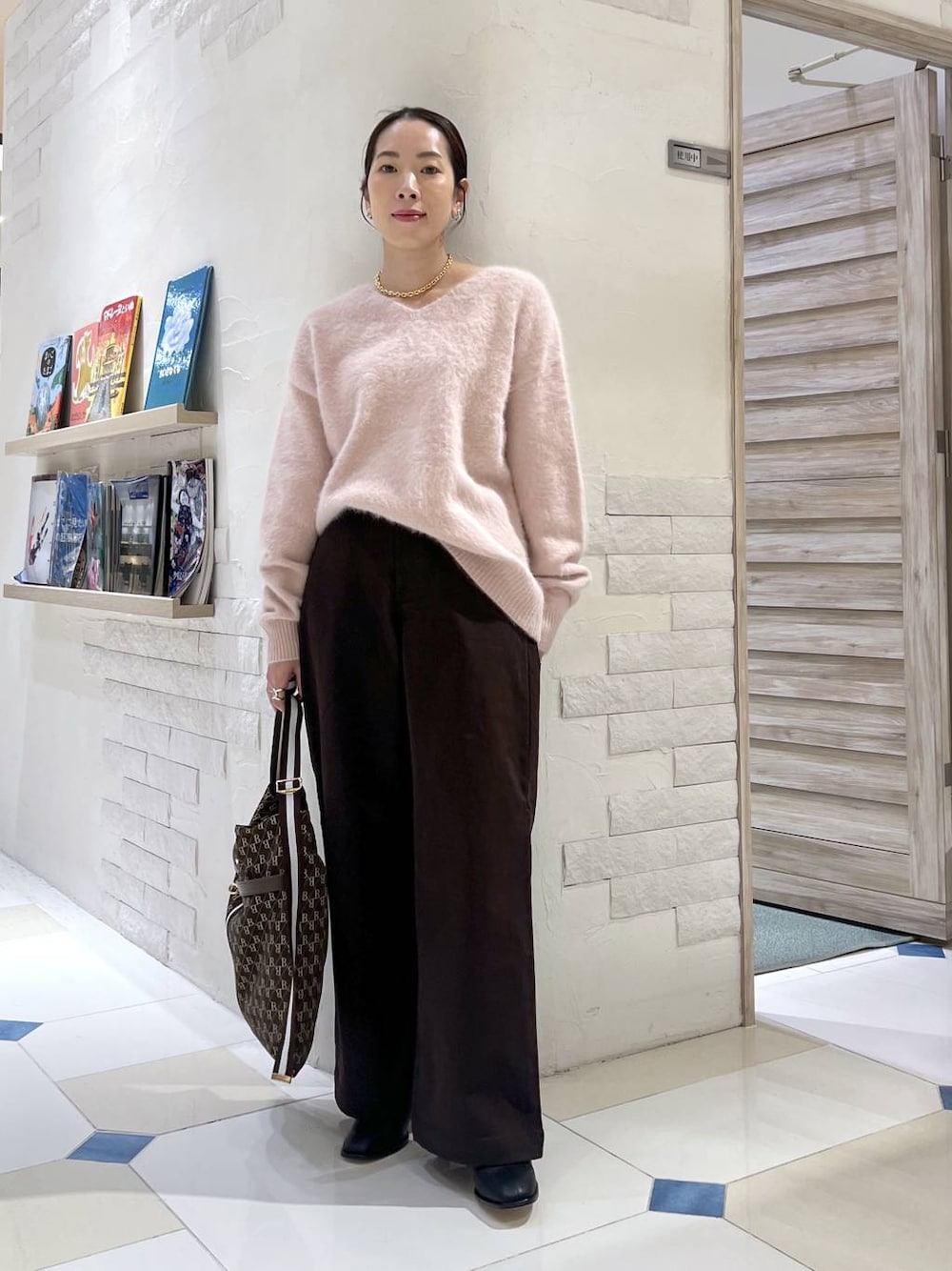 ピンク系のニット/セーター、ブラウン系のショルダーバッグ、ブラック系のブーツを着用したレディースの秋コーディネートの1枚目の写真