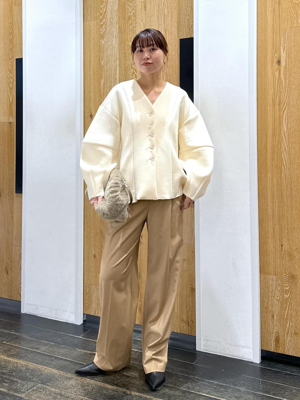 ブラック系のブーツ、ホワイト系のカーディガン/ボレロ、ベージュ系のスラックスを着用したレディースの秋コーディネートの1枚目の写真