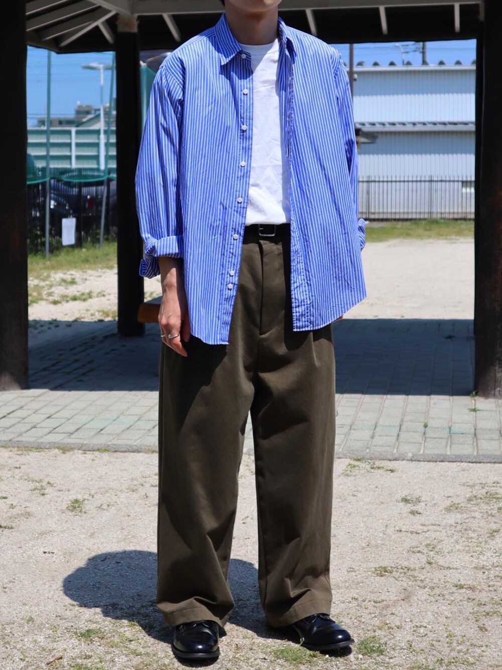 ブルー系のシャツ/ブラウス、ホワイト系のTシャツ/カットソー、グリーン系のチノパンツを着用したメンズの春コーディネートの1枚目の写真
