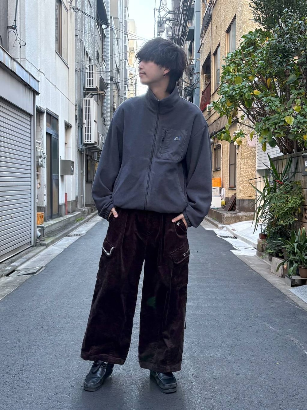 グレー系のブルゾン、ブラック系のニット/セーター、ブラウン系のカーゴパンツを着用したメンズの冬コーディネートの1枚目の写真