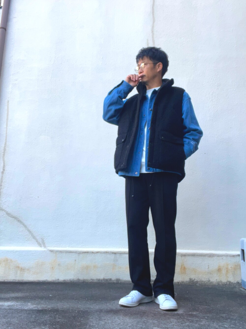 ブラック系のベスト、ブルー系のその他アウター、ホワイト系のスウェットを着用したメンズの秋コーディネートの1枚目の写真