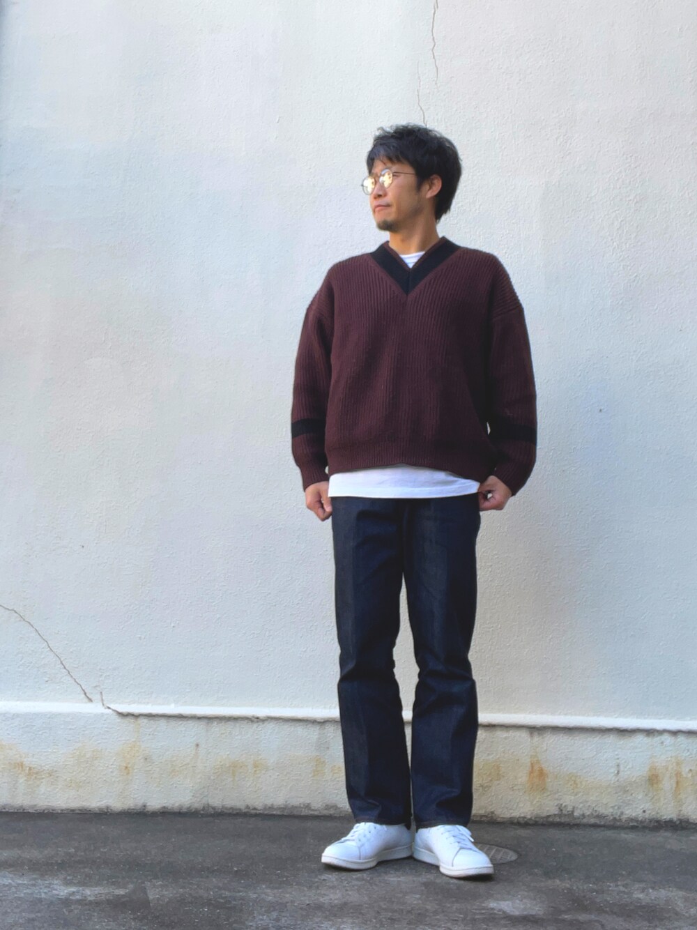 レッド系のニット/セーター、ブルー系のスラックス、ホワイト系のスニーカーを着用したメンズの春コーディネートの1枚目の写真