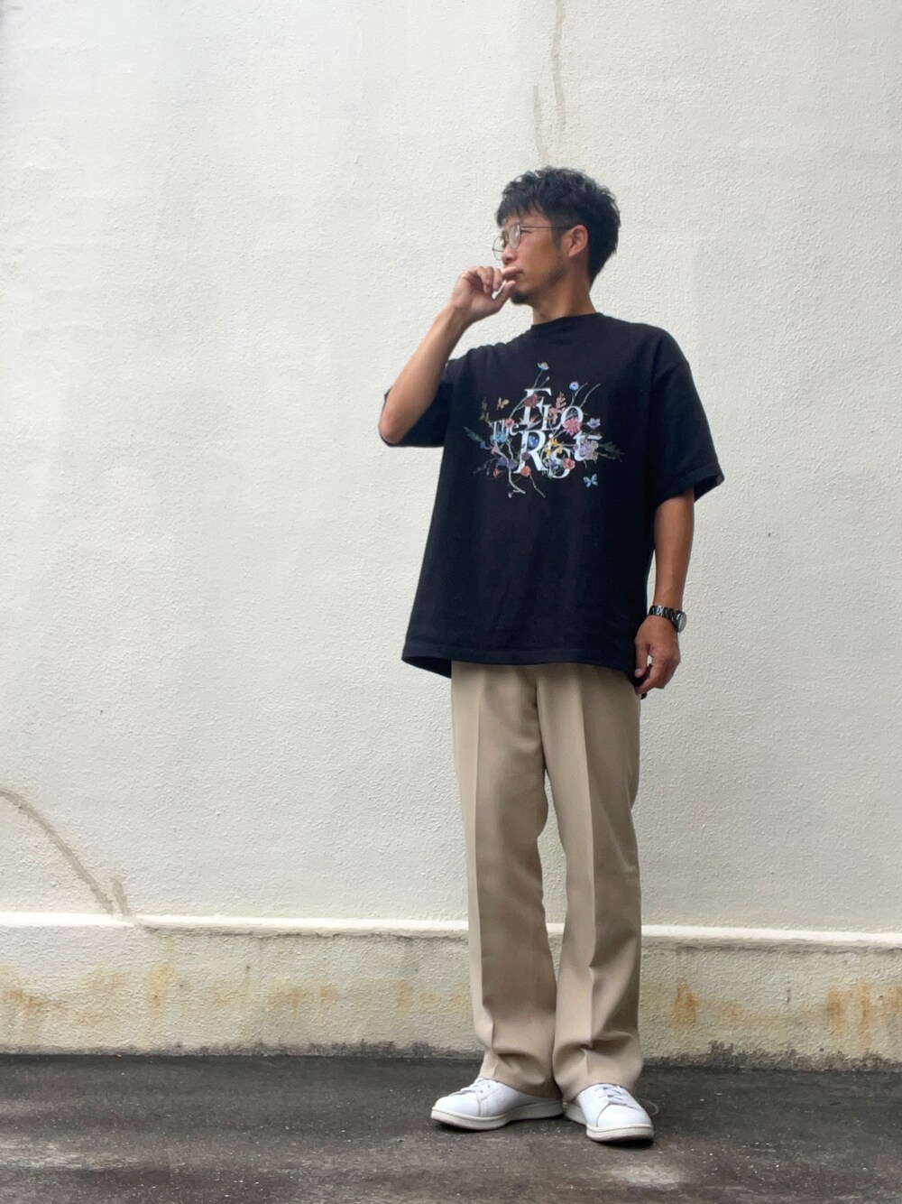ブラック系のTシャツ/カットソー、ベージュ系のスラックス、ホワイト系のスニーカーを着用したメンズの秋コーディネートの1枚目の写真