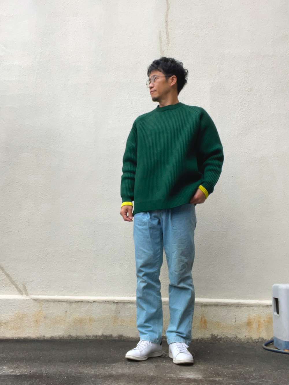 グリーン系のニット/セーター、ブルー系のデニムパンツ、ホワイト系のスニーカーを着用したメンズの冬コーディネートの1枚目の写真