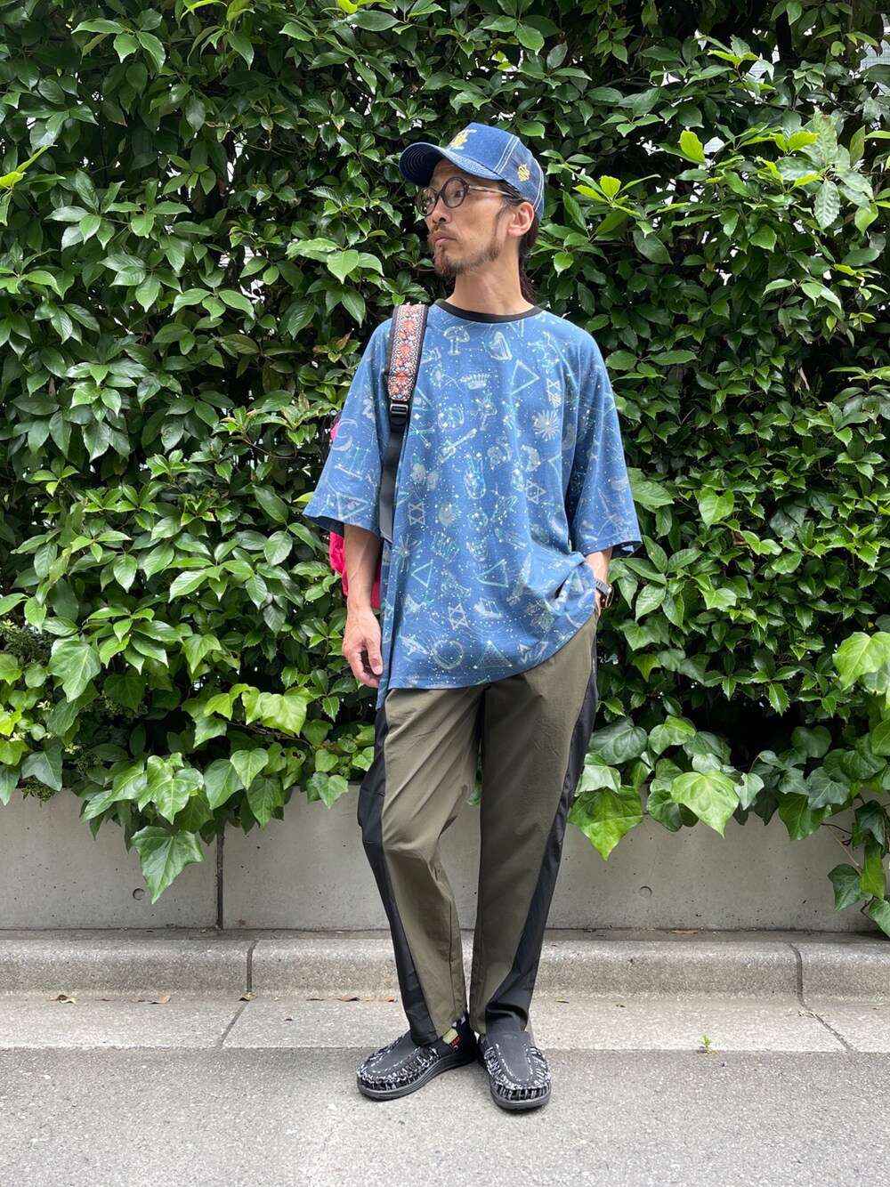ブルー系のTシャツ/カットソー、グリーン系のスラックス、ブルー系のキャップを着用したメンズの夏コーディネートの1枚目の写真