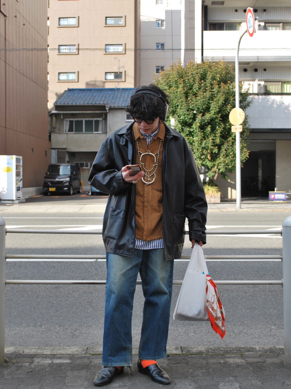 ホワイト系のバッグ、ブルー系のデニムパンツ、ブラック系のジャケット/アウターを着用したメンズの春コーディネートの1枚目の写真