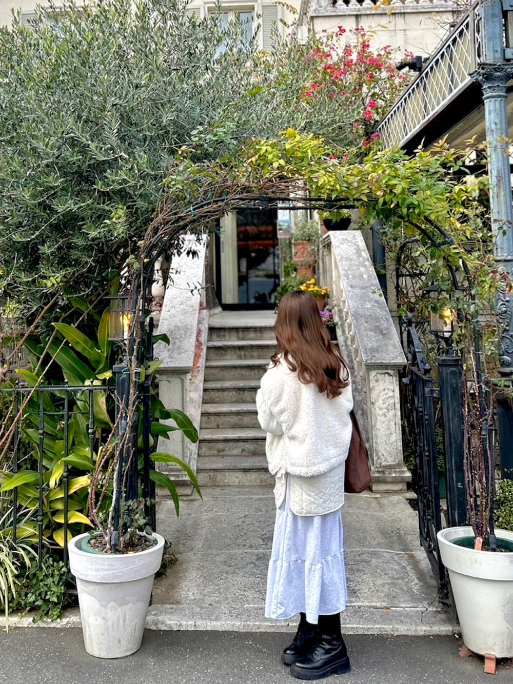 ホワイト系のミリタリージャケット、グレー系のワンピース、ブラック系のブーツを着用したレディースの冬コーディネートの1枚目の写真