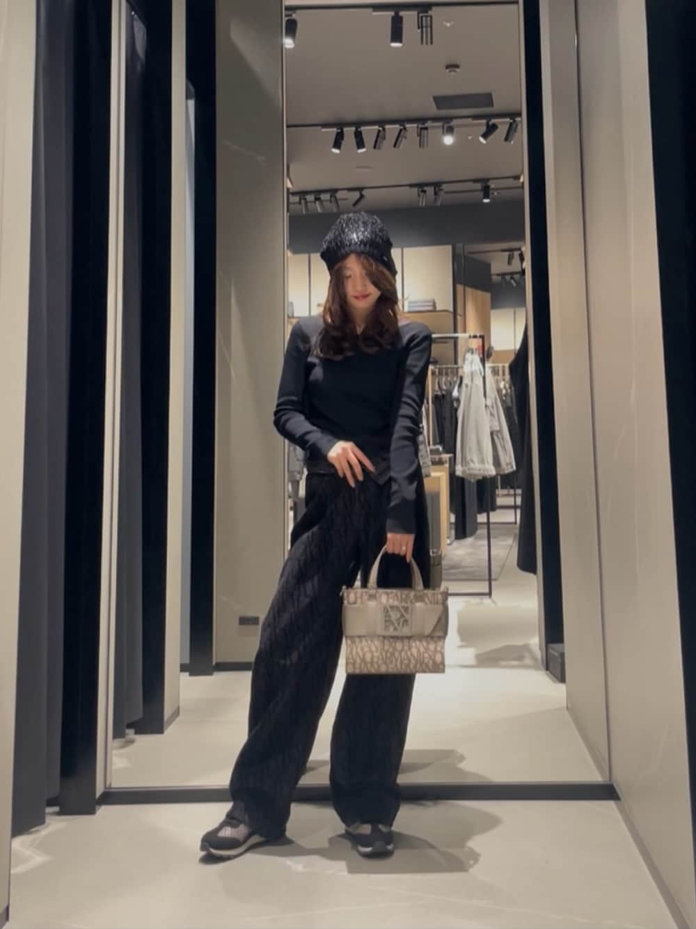 ベージュ系のハンドバッグ、ブラック系のデニムパンツ、ブラック系のニットキャップ/ビーニーを着用したレディースの秋コーディネートの1枚目の写真