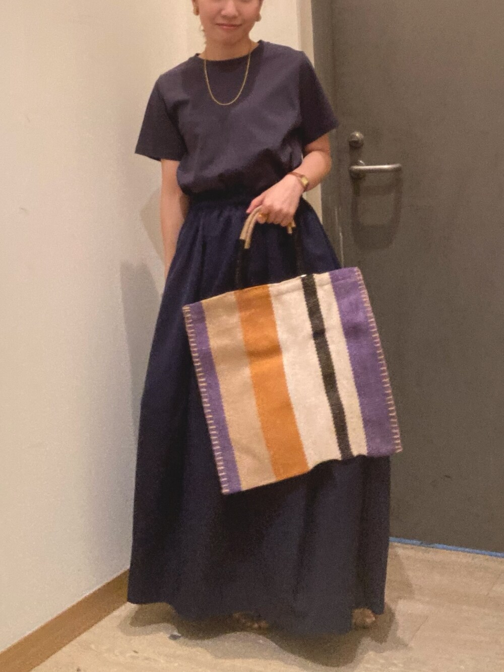 グレー系のワンピース、ブルー系のトートバッグ、ベージュ系のサンダルを着用したレディースの春コーディネートの1枚目の写真