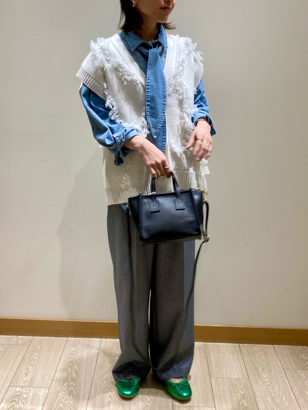 ブラック系のトートバッグ、ブルー系のスラックス、グリーン系のバレエシューズを着用したレディースの冬コーディネートの1枚目の写真