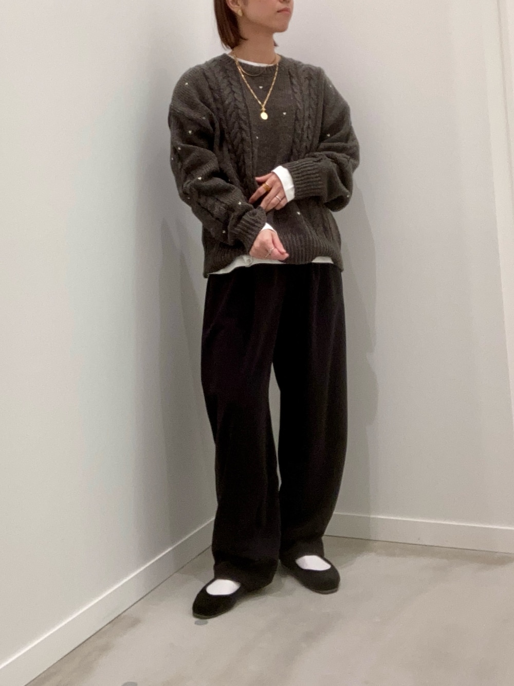 グレー系のニット/セーター、ホワイト系のTシャツ/カットソー、ブラック系のその他パンツを着用したレディースの秋コーディネートの1枚目の写真