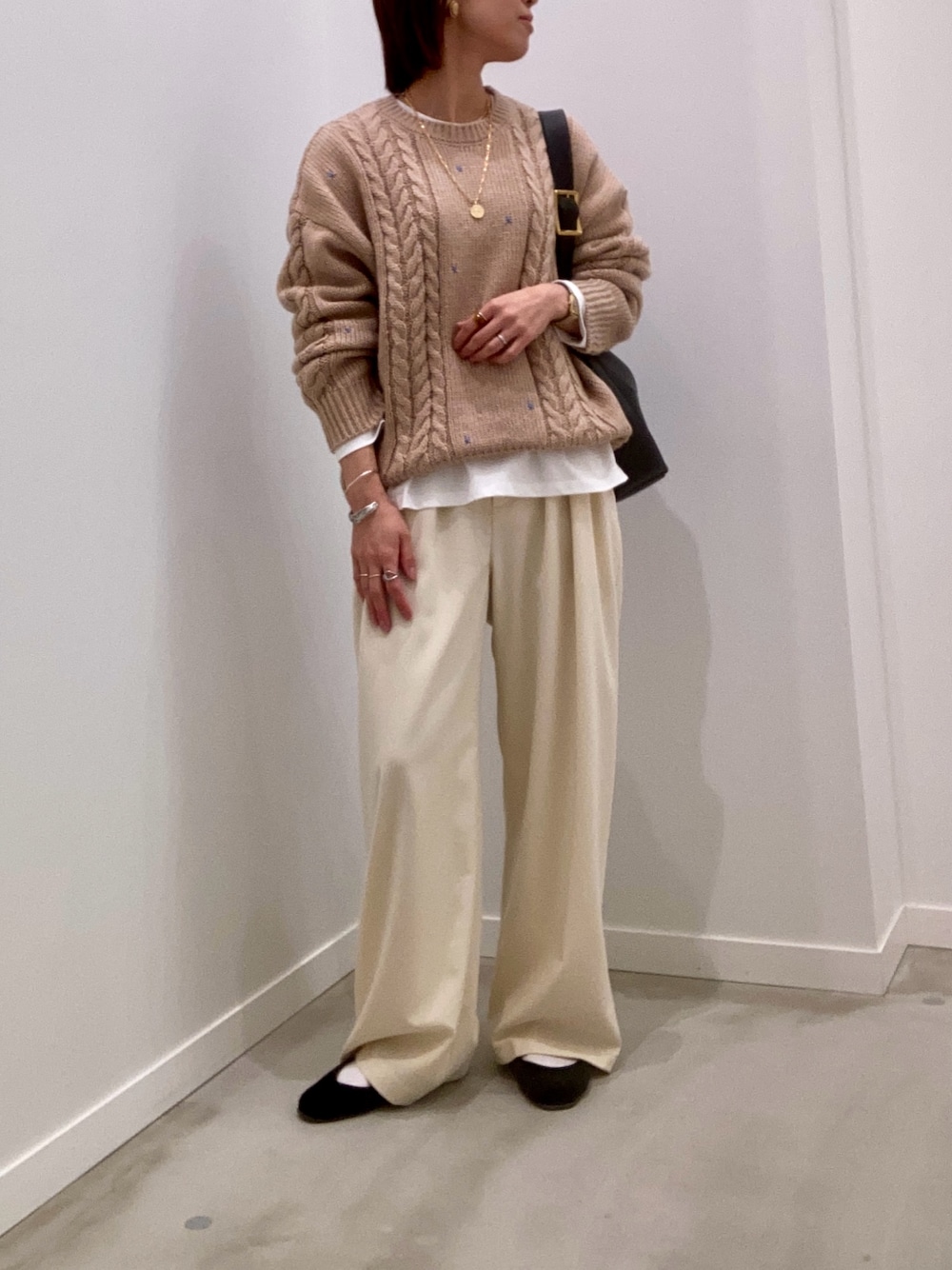 ベージュ系のニット/セーター、ホワイト系のTシャツ/カットソー、ブラック系のショルダーバッグを着用したレディースの秋コーディネートの1枚目の写真