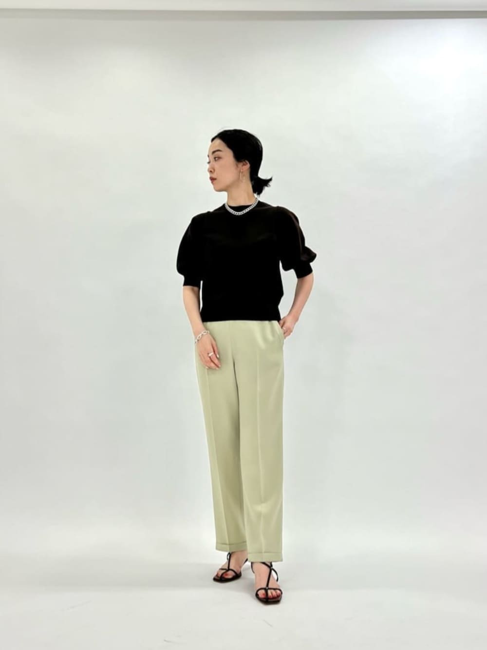 ブラウン系のニット/セーター、グリーン系のその他パンツ、ブラック系のサンダルを着用したレディースの春コーディネートの1枚目の写真