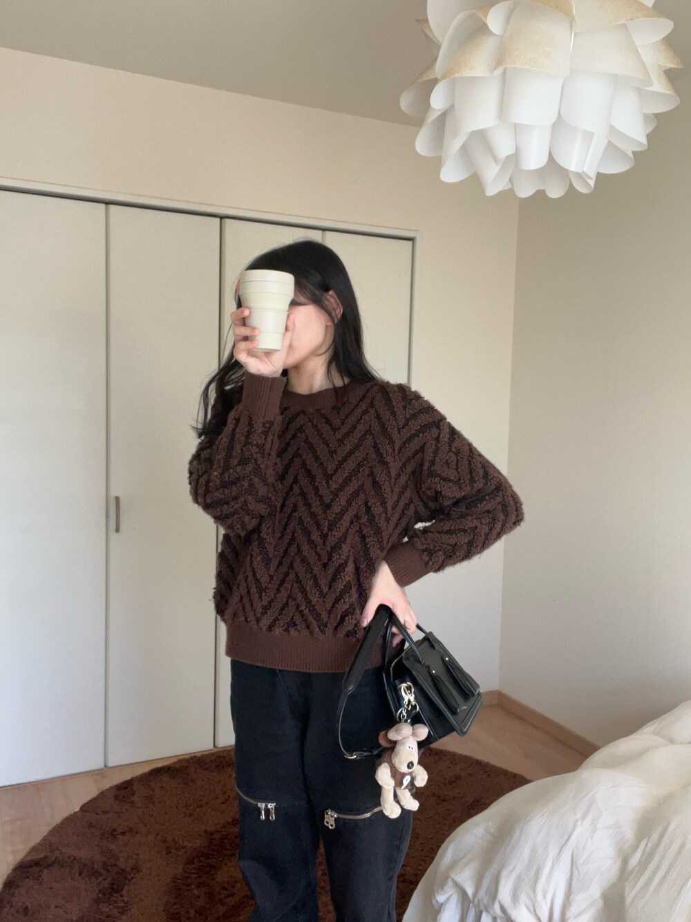 ブラック系のショルダーバッグ、ブラック系のデニムパンツ、ブラウン系のニット/セーターを着用したレディースの冬コーディネートの1枚目の写真